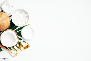 Organic cosmetic with coconut and palm leaf on white background. Flat lay, top view, copy space. Natural beauty product, body care and skin treatment concept