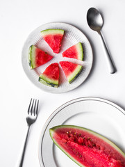 Sliced Watermelon on white plate with spoon and fork stock photo with bright background.

