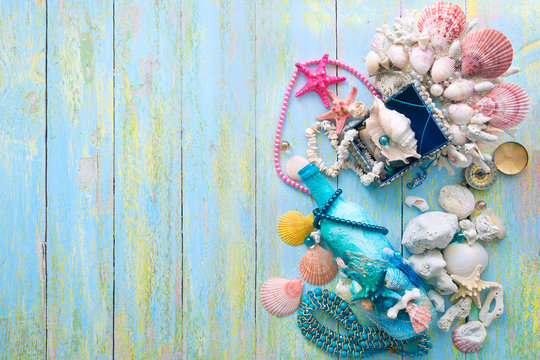 crown casket and bottle decorated with shells and mermaid decorations out of focus on a wooden background with blur