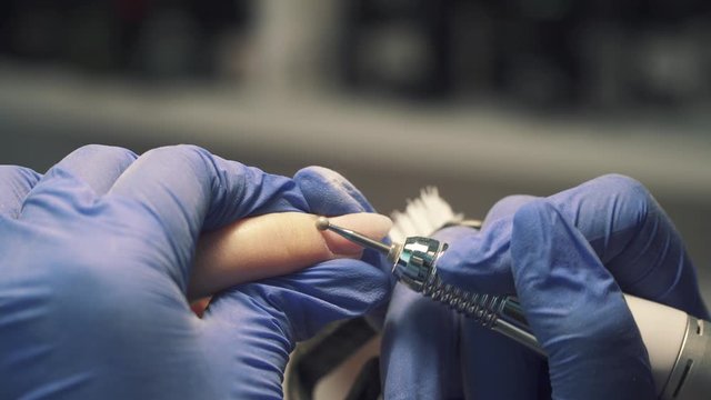 Removing the cuticle on the fingers with a round mill in a beauty salon during manicure