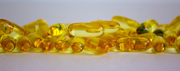 Yellow vitamins tablets, fish oil, Omega Vitamin E. Pills on a white background. Web banner with a copy space.