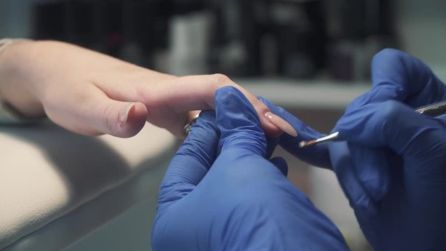 Removing the cuticle on the fingers with a round mill in a beauty salon during manicure