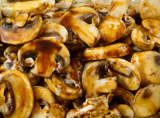 Closeup of raw fresh mushroom slices covered in savory brown sauce for baking