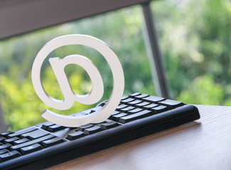 clean at-symbol, at-sign on keyboard with wood surface, symbol for mail, internet, websites and...