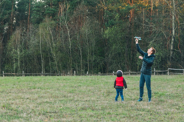 father playing with toddler daughter at field with toy plain
