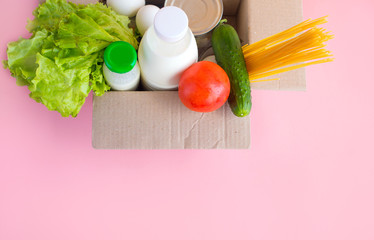 Donation box with various food. Open cardboard box with canned goods, milk, eggs, salad, spaghetti.