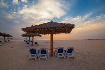UAE, landscape sea, sunset, beach umbrella and sunbeds