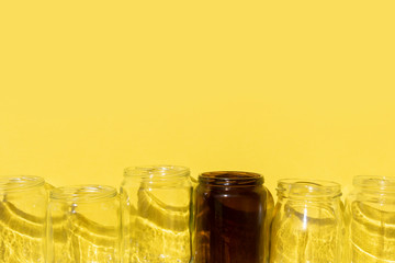 empty glass bottles with shadows on yellow background
