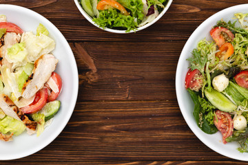 white deep plates with fresh salad ingredients mixed with sauce placed on an attractive background. A place for a menu, banner or advertisement