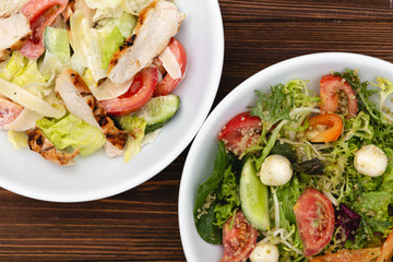 white deep plates with fresh salad ingredients mixed with sauce placed on an attractive background. A place for a menu, banner or advertisement
