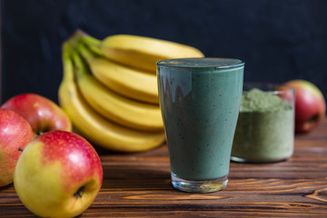 Fresh mixed green fruit smoothie with matcha powder in a glass cup with a straw. Solid background, copy space