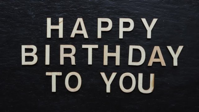 Stop motion of wooden letters writing HAPPY BIRTHDAY on slate background