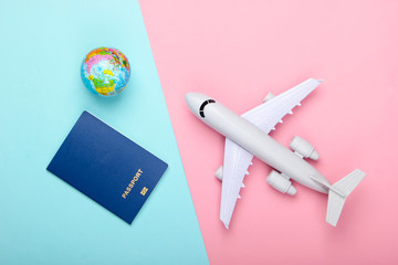 Tourism and travel concept. Emigration. Globe,  passport and passenger plane figurine on pink blue pastel background. Top view. Flat lay