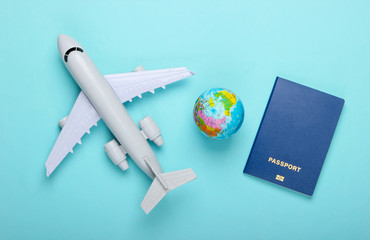 Tourism and travel concept. Globe, passport, passenger plane figurine on blue pastel background....