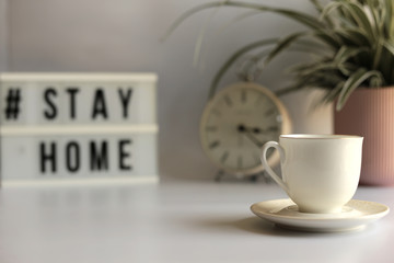 Home office desc with cup of coffee, stationary, home plant and Stay Home sign. Stay  home concept,  office desc concept during pandemic