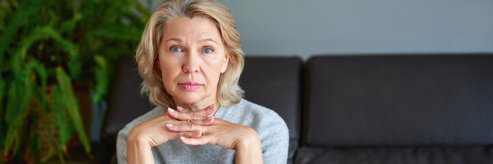 middle-aged blond woman sitting on a sofa at home