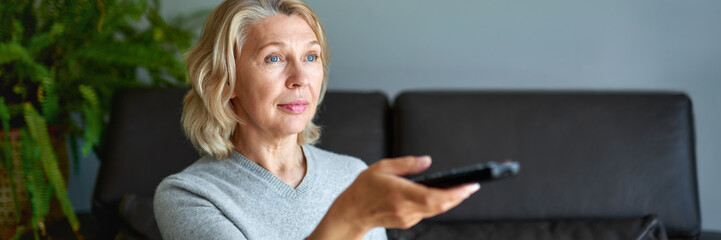 Mature senior woman watching television at home