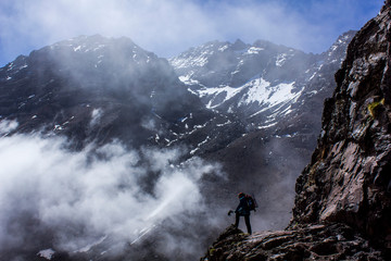 Obraz premium spectacular panorama of a mountaineer hiking in the great atlas of morocco with the jebel toubkal peak in the background
