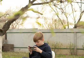 Fototapeta premium Caucasian blond boy plays on smartphone