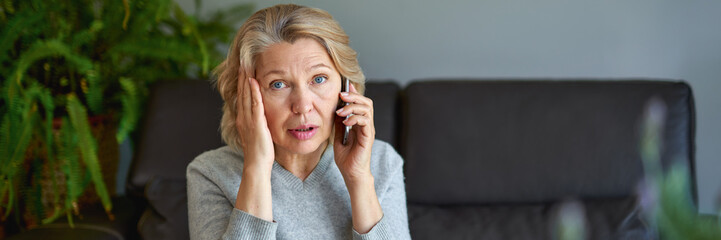 mature woman using mobile phone while sitting on sofa at home