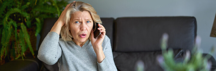 Fototapeta premium mature woman using mobile phone while sitting on sofa at home