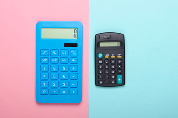 Two calculators on blue pink pastel background. Top view.