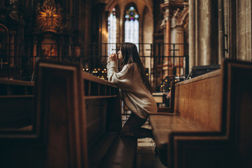 a woman praying on her knees in an ancient Catholic temple to God. copy space