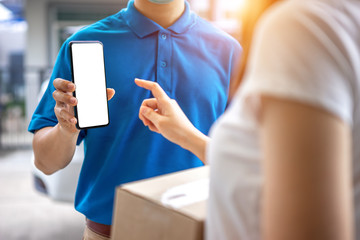 Asian deliveryman is delivering a package to a female customer in front her house. For her to sign to receive the product After she ordered online during the outbreak of coronavirus or Covid-19 virus.