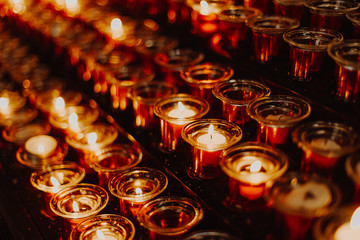 religion, faith, harmony and people concept: many small candles lit in the church