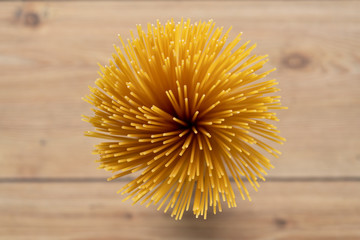 Row, uncooked spaghetti bunched together. Italian pasta or macaroni. Bird eye, top view, wooden table background. Dry pasta products. Handful of uncooked spaghetti pasta. Portion Of Spaghetti