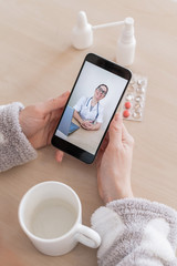 Unrecognizable woman on online consultation with a doctor on a cell phone. The girl is sick and talks to the attending physician on a video call from home. Close-up of the screen.