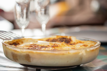 gratin cannelloni with bechamel and cheese in a glass tray