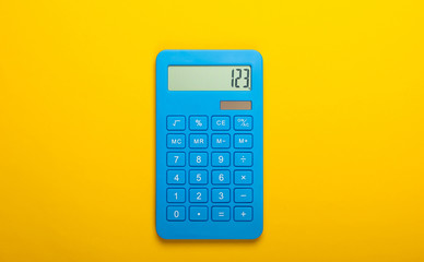 Blue calculator on a yellow background. Calculation or counting. Minimalism. Top view