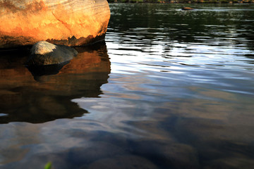 beautiful ripples on river flow over colorful stones in summer sunshine