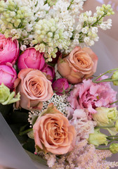 Young woman holding delicate flower bouquet. Bouquet of fresh beautiful flowers wrapped in pink paper. Mother`s day.