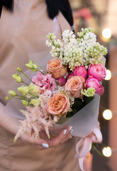 Young woman holding delicate flower bouquet. Bouquet of fresh beautiful flowers wrapped in pink paper. Mother`s day.