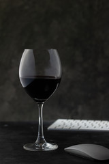 Copa de vino tinto y computadora. Teclado y mouse