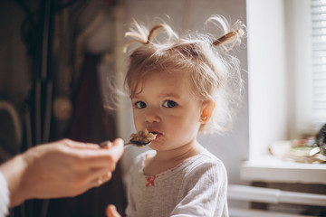 selective focus, noise effect: a pretty child girl, together with her mother have breakfast in the morning in the kitchen