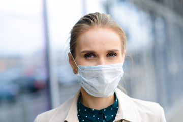 A young businesswoman wearing a health mask and talking on the phone in the city