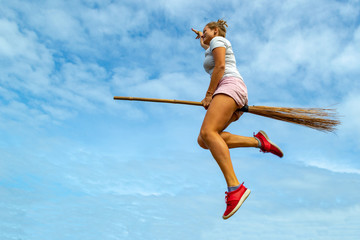Young woman flying on the broom in the blue sky of Siquijor
