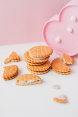Obraz na płótnie Canvas Sweet creamy filling crackers on a white-pink pastel background. 