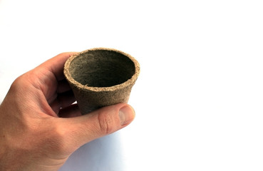 Hand grabbing a small peat pot vase isolated on white background