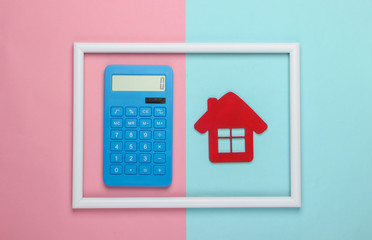 Calculator and red house in a white frame on pink blue background. Concept art photo. Top view. Minimalism