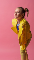pretty sweet girl smiling leans her hand on leg and looking on empty space in pink background