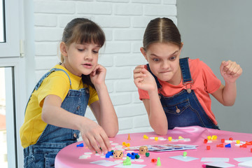 Girls play board games, one of them looks funny at the chips