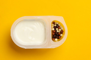 Quen in a plated box with chocolate corn balls on a yellow background. Top view. Minimalism food concept.