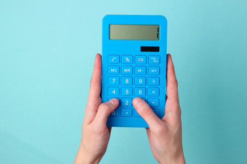 The hand presses the buttons blue calculator on blue background. - obrazy, fototapety, plakaty