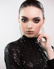 Portrait of a young beautiful elegant woman. Black sequin evening dress. Bright makeup and smoothly...