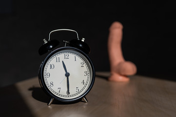 Time for carnal pleasures. Alarm clock and dildo made of cyber leather. Naturalistic vibrator for masturbation.