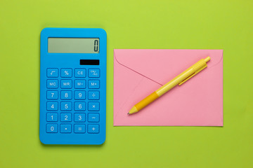 Calculator with envelope on green background. Top view